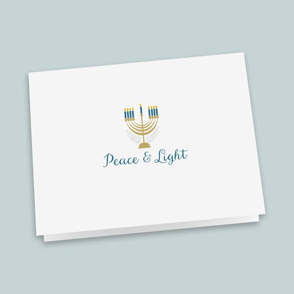 A white greeting card with a stylized graphic of a menorah and the text "Peace & Light" printed on it.