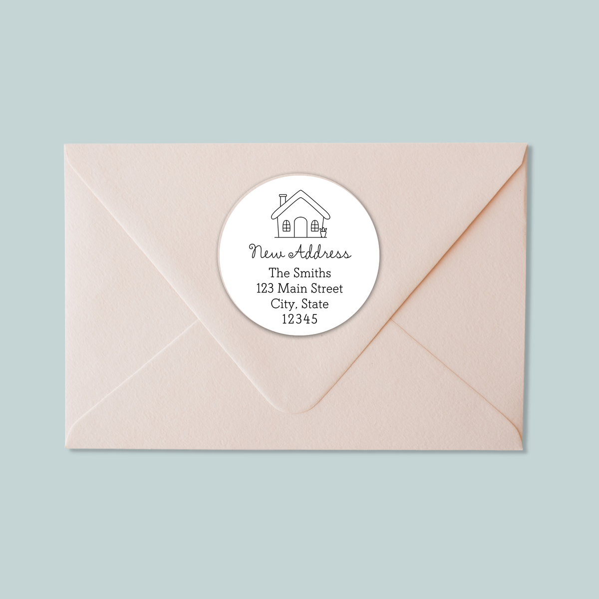 A light pink envelope with a white circular label on it, which contains text and a house illustration.
