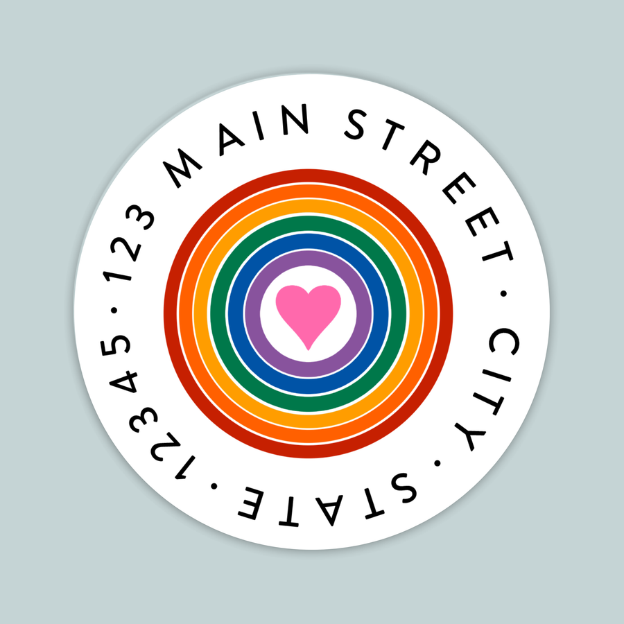 A circular white label with a rainbow-colored heart in the center, surrounded by the text "MAIN STREET CITY STATE" in a circular pattern.