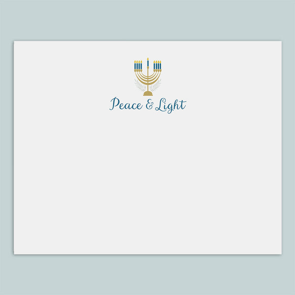 A white envelope with a graphic design featuring a menorah and the text "Peace & Light" printed on it.