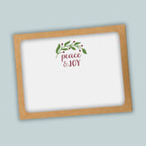 A white card with a brown frame, featuring a decorative wreath and the text 