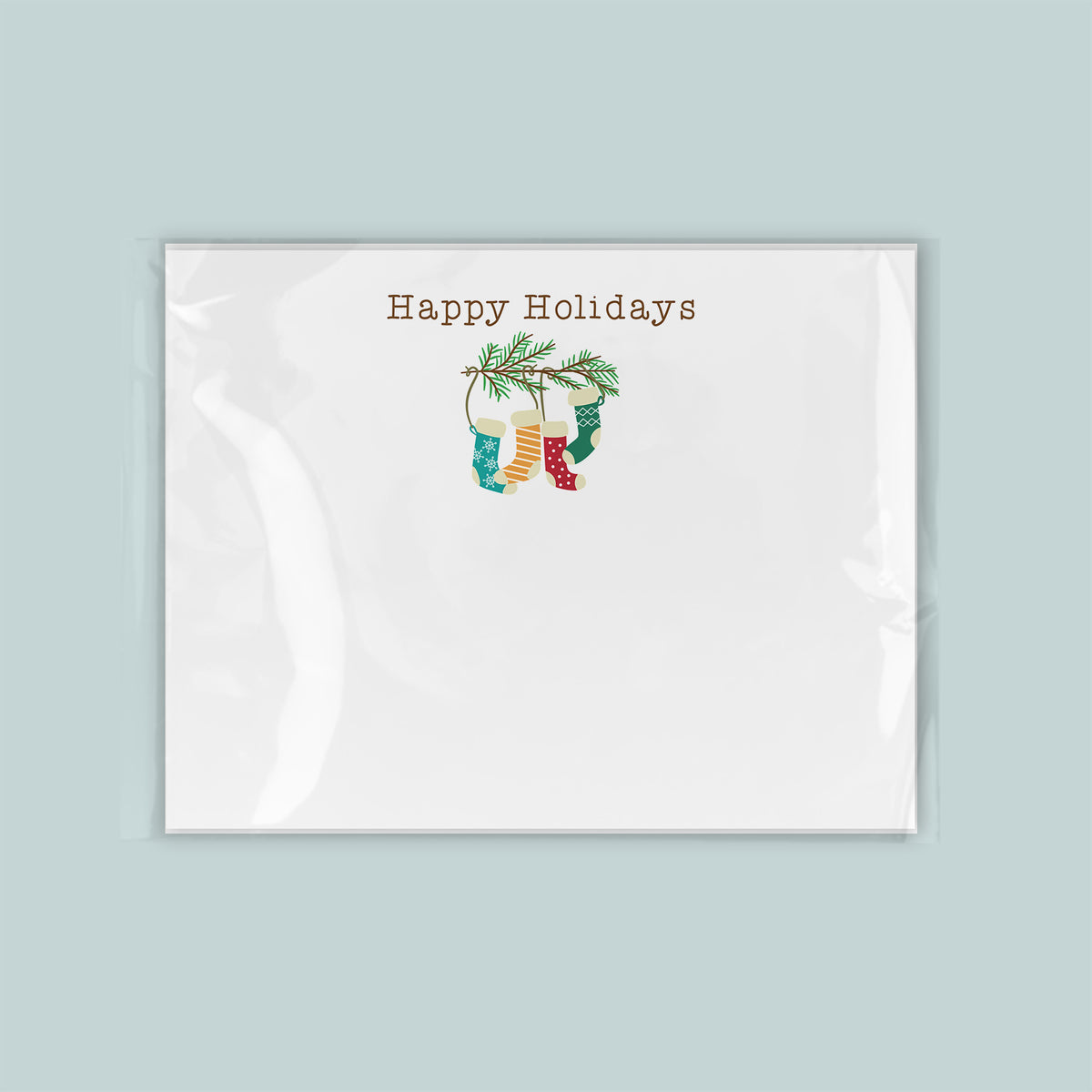 A white greeting card with a festive holiday design featuring a pair of colorful stockings hanging from a branch.