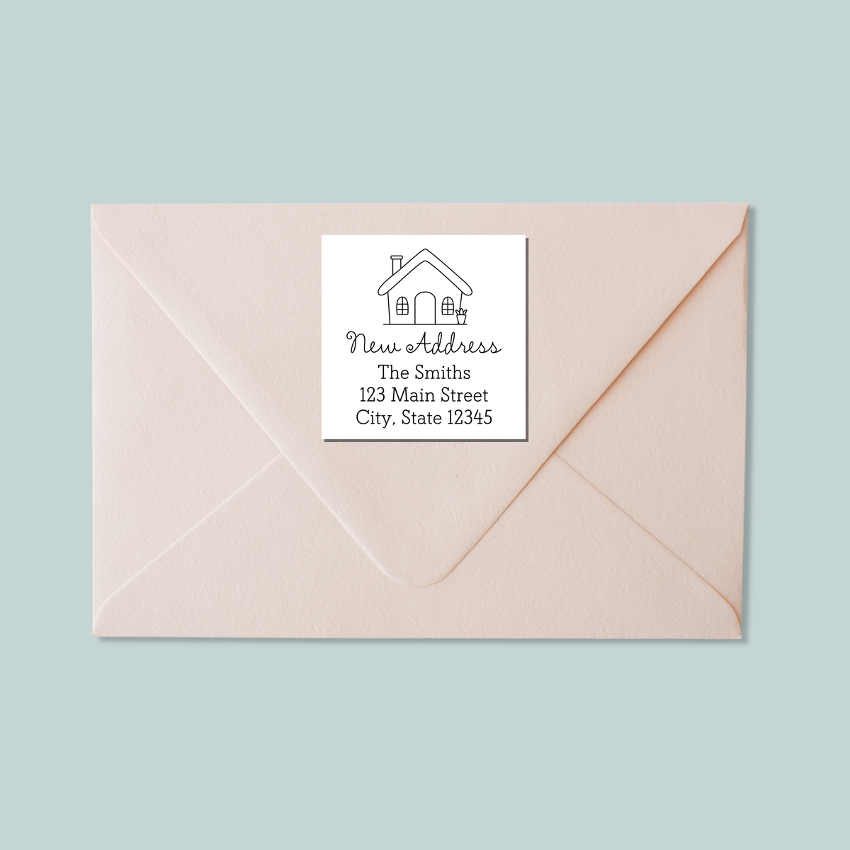 A light pink envelope with a white label that reads "New Address The Smiths 123 Main Street City, State 12345".