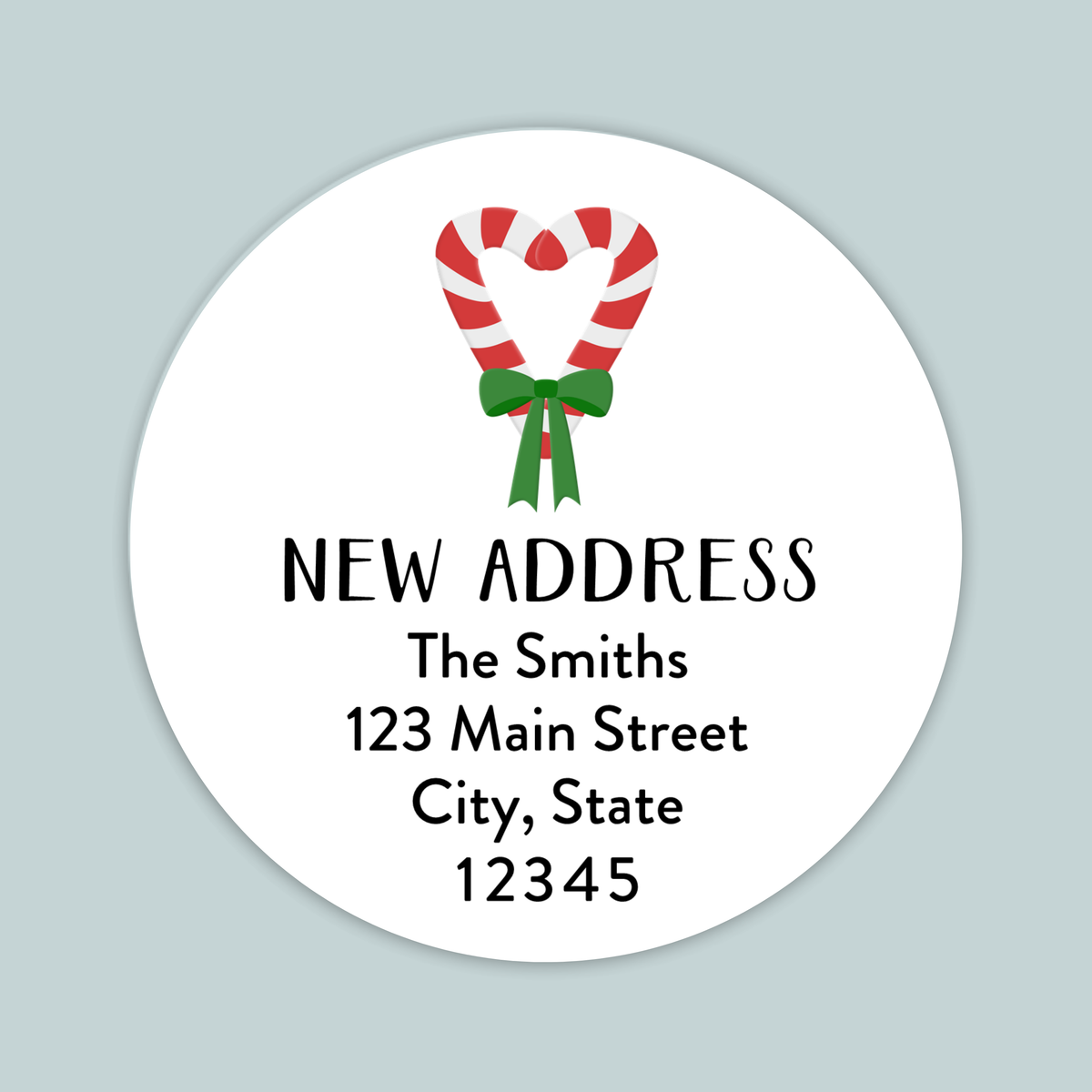 The image is a white circular label with a red and white striped candy cane and a green ribbon, along with text that reads "NEW ADDRESS The Smiths 123 Main Street City, State 12345".