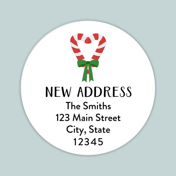The image is a white circular label with a red and white striped candy cane and a green ribbon, along with text that reads "NEW ADDRESS The Smiths 123 Main Street City, State 12345".