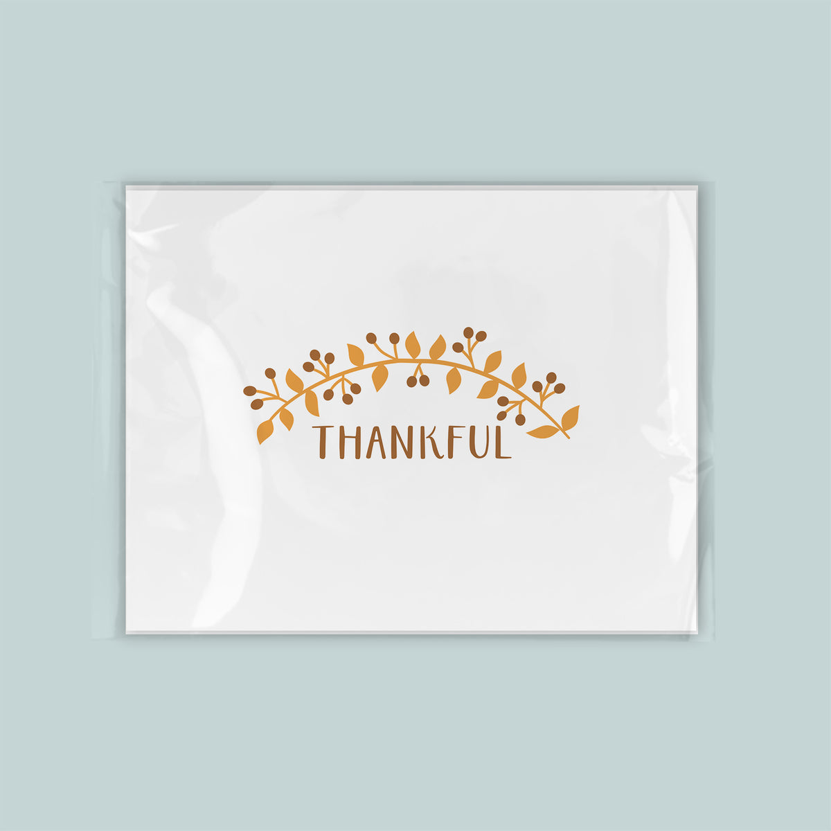 A white rectangular card with a decorative leaf design and the word "THANKFUL" written on it.
