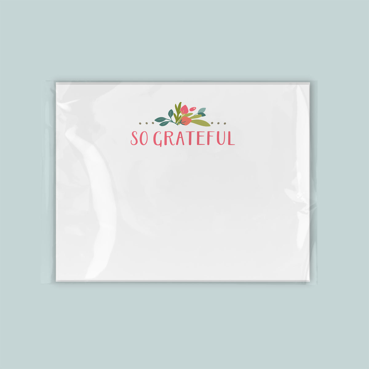 A white square with the text "So Grateful" written on it, along with a decorative floral design.