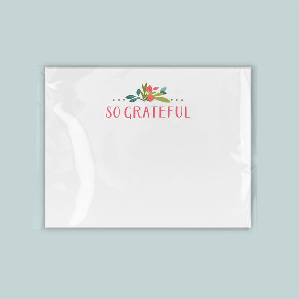 A white square with the text "So Grateful" written on it, along with a decorative floral design.
