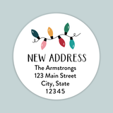a white circular label with a festive design featuring colorful Christmas lights. The label has text that reads 