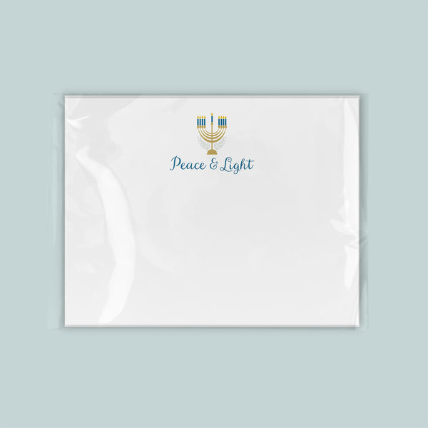 A white envelope with a blue and gold design featuring a menorah and the text "Peace & Light" printed on it.