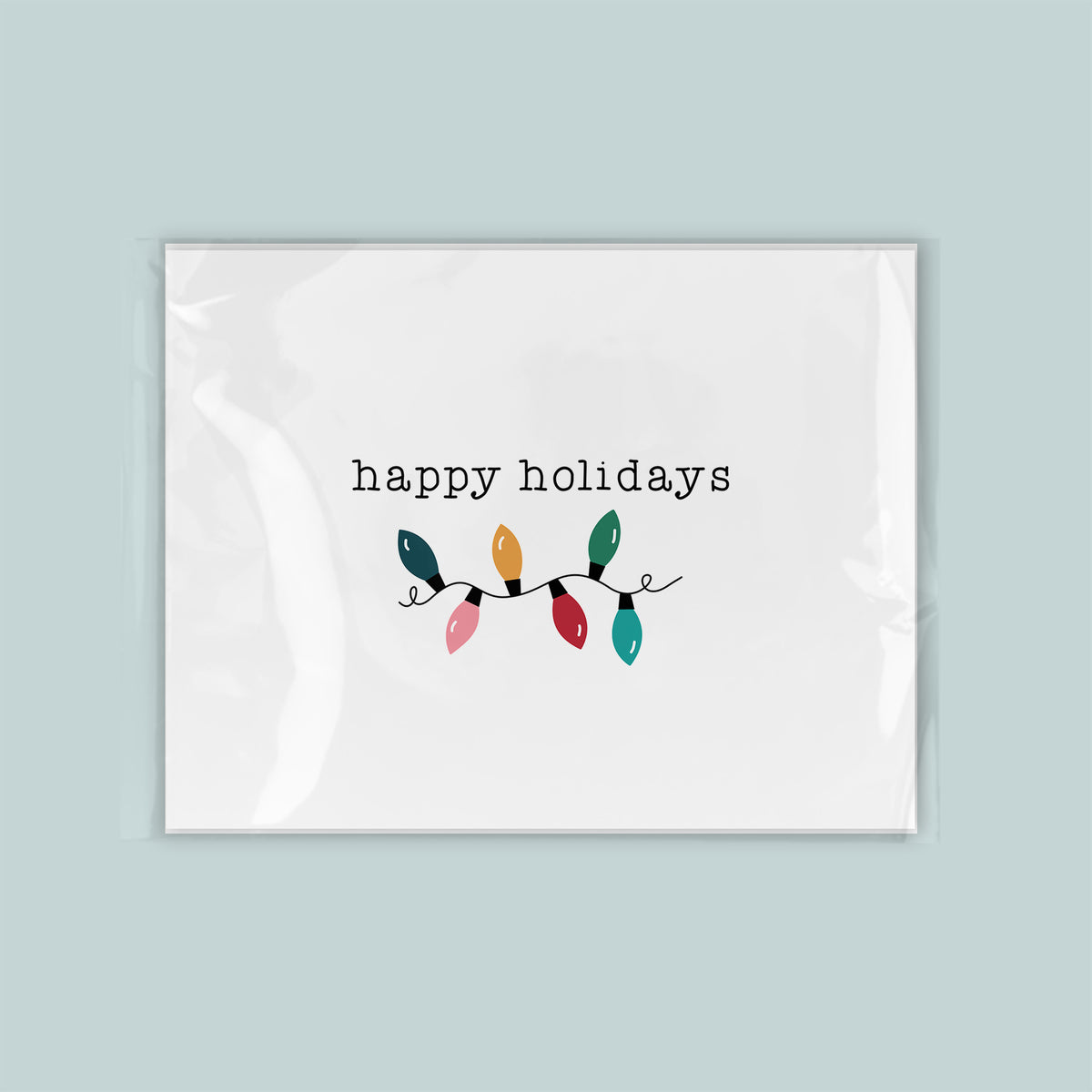 A white rectangular card with the text "happy holidays" and a decorative line of colorful Christmas lights.
