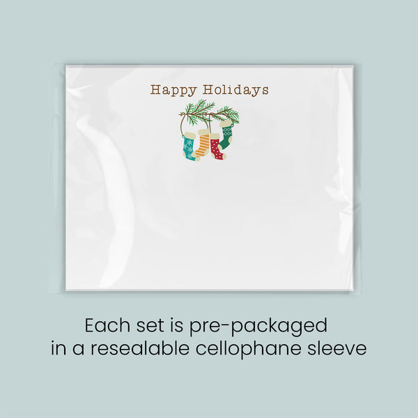 A white greeting card with a festive holiday design, including a stocking and a pine branch. The card is pre-packaged in a reesealable cellophane sleeve.
