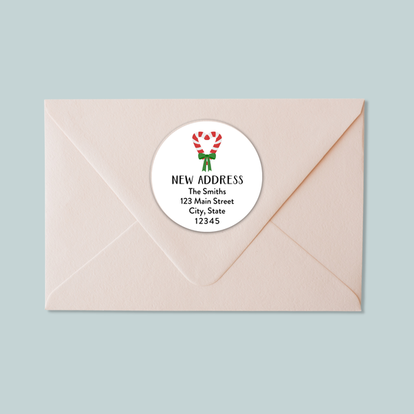 A light pink envelope with a white circular label that reads "NEW ADDRESS The Smiths 123 Main Street City, State 12345".