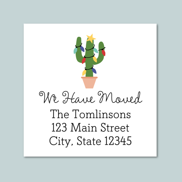 The image is a white envelope with a festive Christmas tree decoration on it. The text on the envelope reads "We Have Moved The Tomlinson's 123 Main Street City, State 12345".