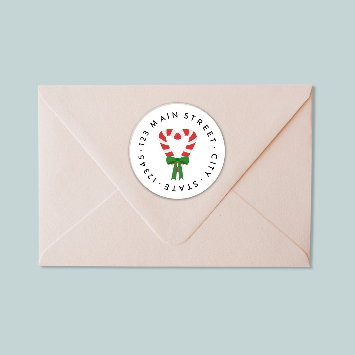 A light pink envelope with a white circular label featuring a red and white striped candy cane design.