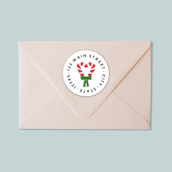 A light pink envelope with a white circular label featuring a red and white striped candy cane design.