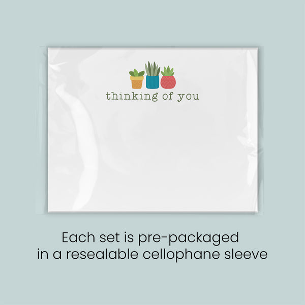 A set of pre-packaged greeting cards, each set in a resealable cellophane sleeve, with a simple design featuring three potted plants and the text "thinking of you".