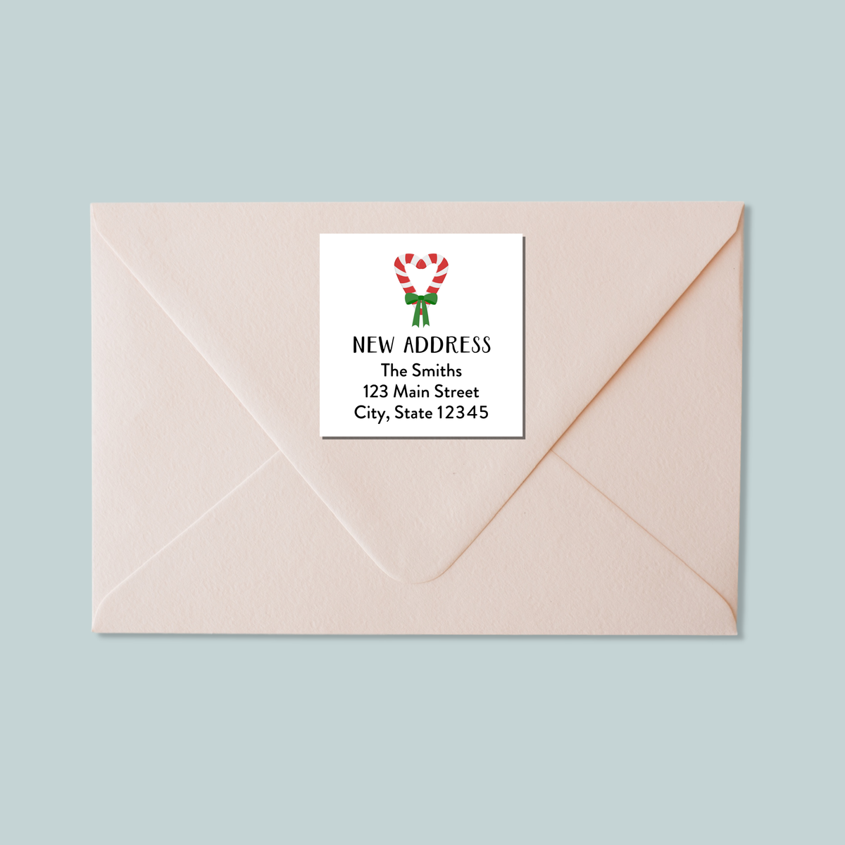A light pink envelope with a white label that reads "NEW ADDRESS The Smiths 123 Main Street City, State 12345".