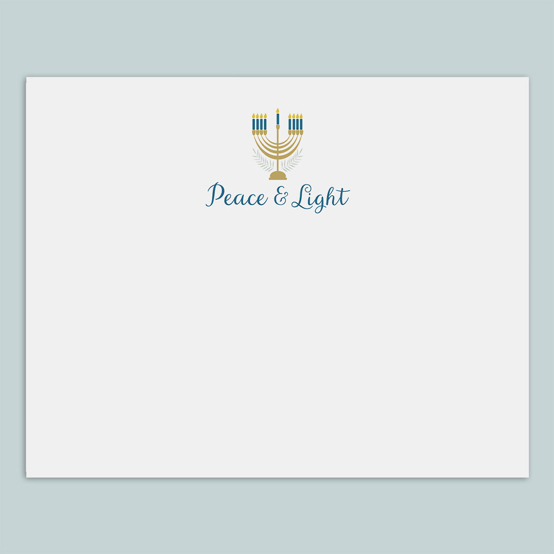 A white envelope with a graphic design featuring a menorah and the text "Peace & Light" printed on it.