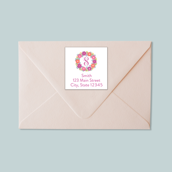 A light pink envelope with a label on it, featuring a floral wreath design and the number 8.