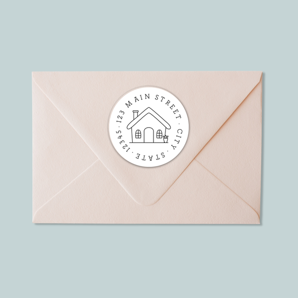A light pink envelope with a white circular stamp featuring a house illustration and text.