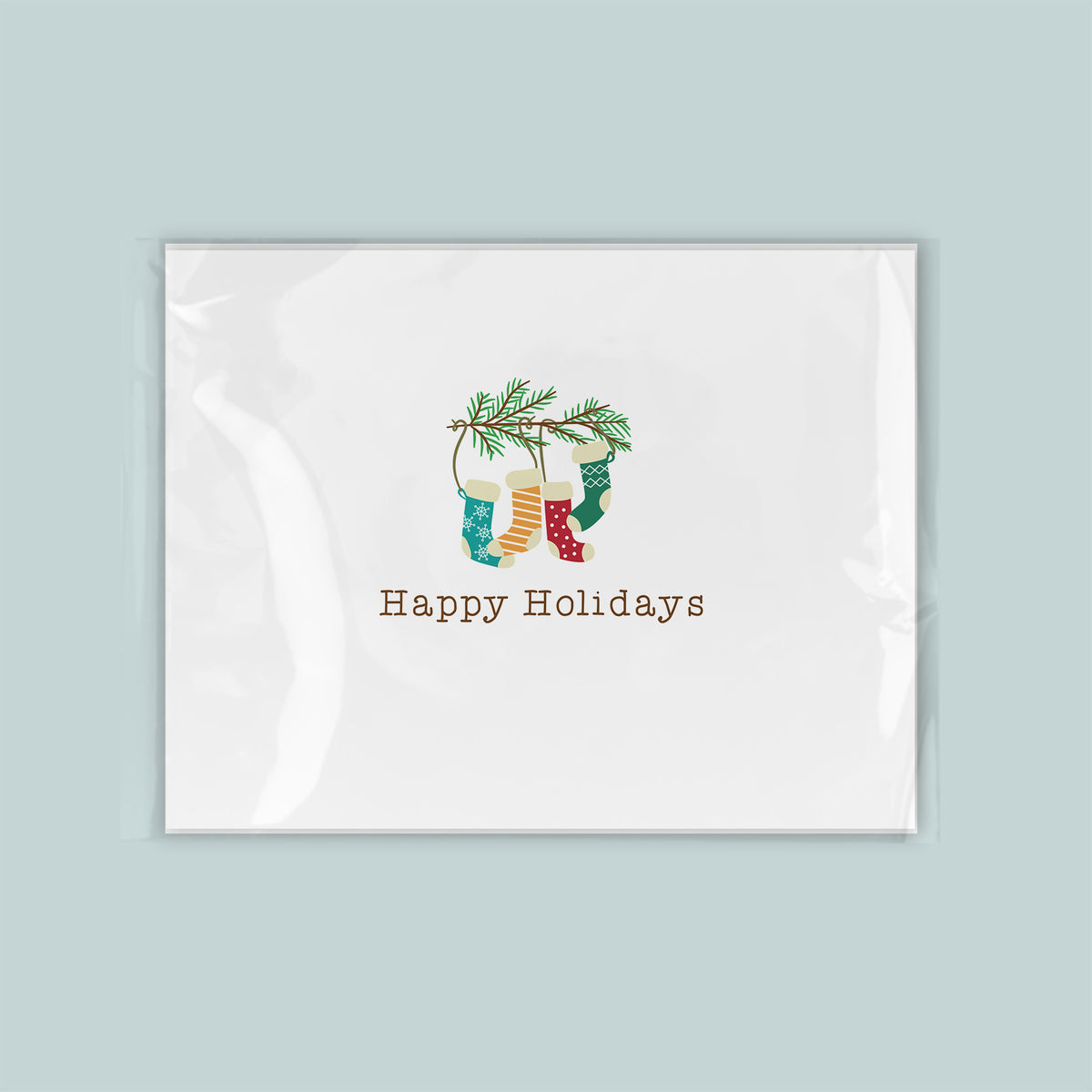 A white greeting card with a festive design featuring colorful Christmas stockings and a pine tree branch.