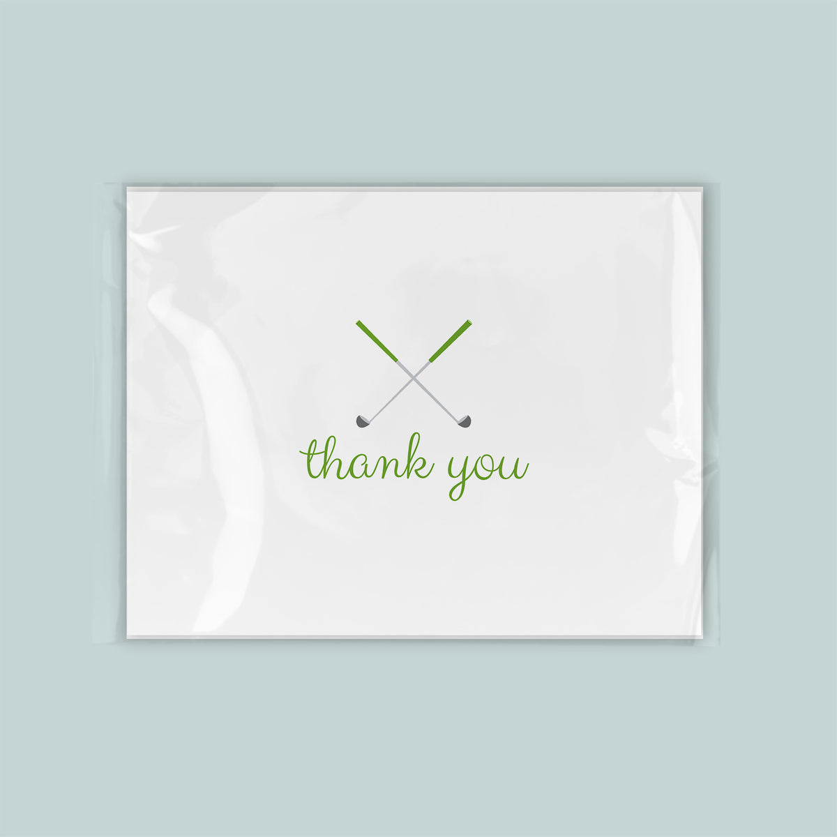 A white card with a green cursive text that says "thank you" and a graphic of two crossed golf clubs.