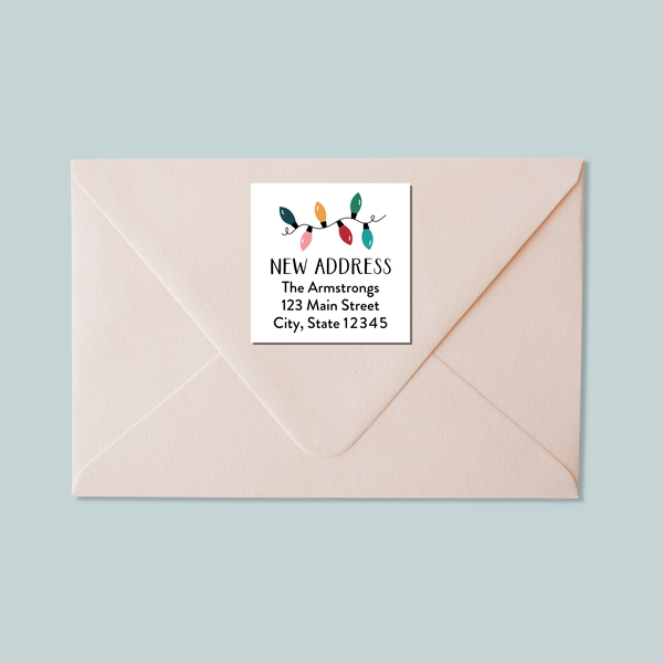 A light pink envelope with a white label that reads "NEW ADDRESS The Armstrons 123 Main Street City, State 12345".